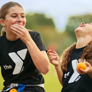 2 girls laughing and eating oranges