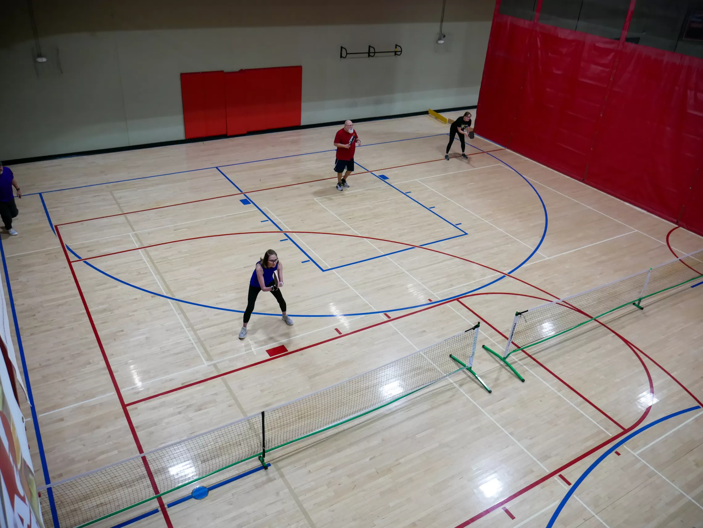 wide shot of people playing on an indoor pickleball court
