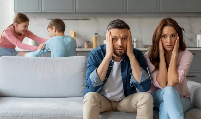 stressed out parents with kids fighting in the background