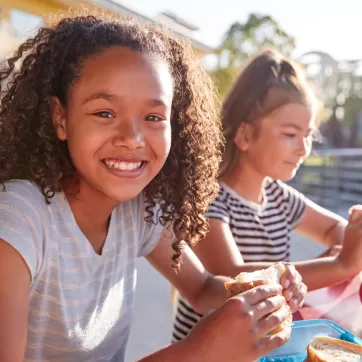 two happy girls eating lunch outside