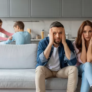 stressed out parents with kids fighting in the background
