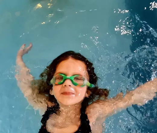 child floating on their back in an indoor pool
